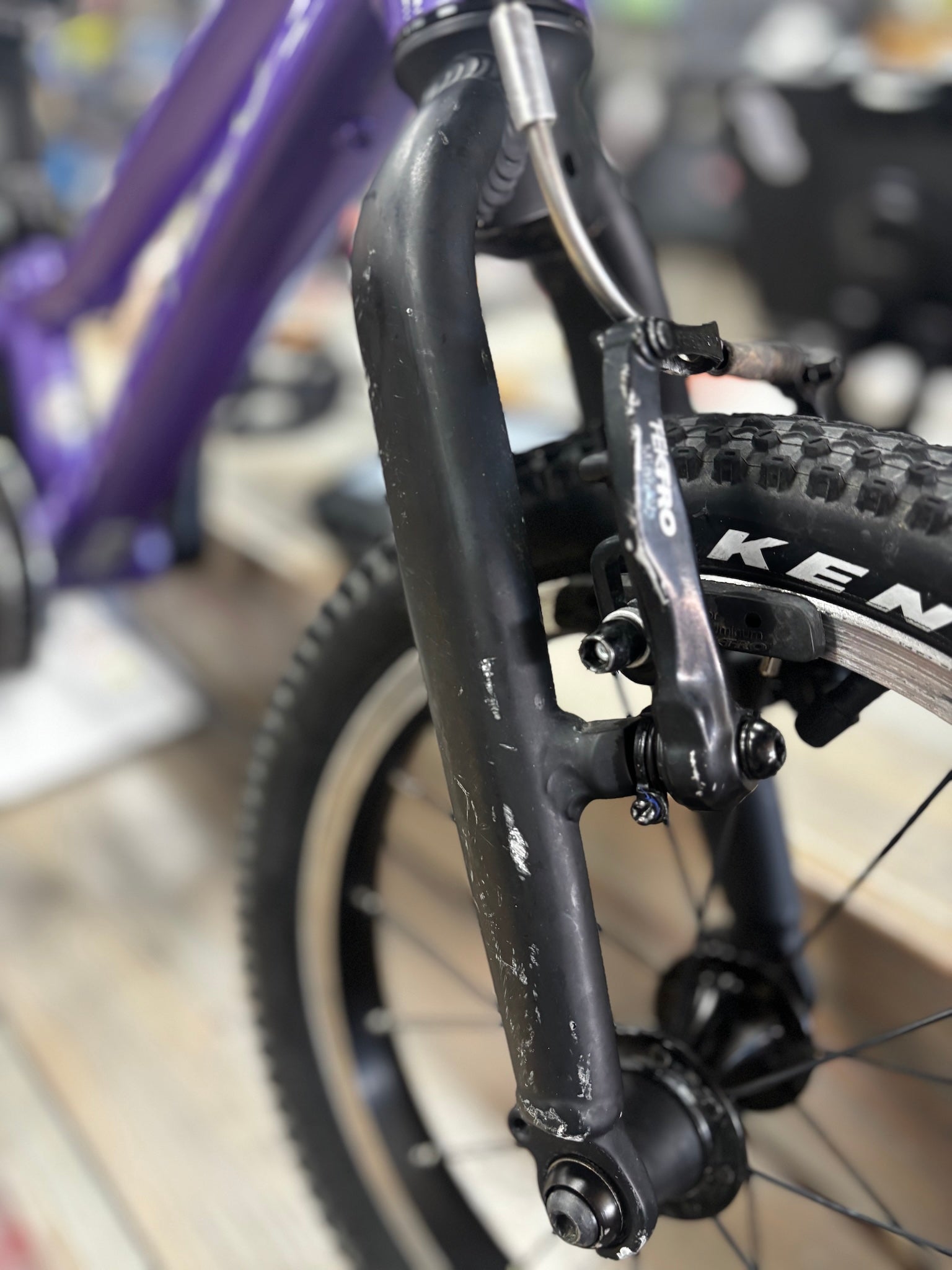 Angled view of a pre-loved Prevelo Alpha One 14" kids' bike in Power Purple, displayed on a dirt trail, featuring a lightweight frame and rugged tires for young adventurers.
