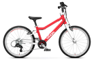 The Woom Go 4 is a red and white lightweight kids’ bike for ages 6+ with an ultralight aluminum frame, black seat, and knobby tires. Shown from the side on a white background, the Woom brand name appears on the frame. Available at CyclErie.