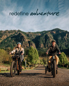 Two people riding Aventure 3 ebikes on a road with mountains available at CyclErie in Erie, CO.