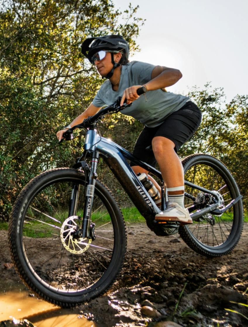Rider on the Aventon Ramblas ADV hardtail eMTB on a dirt trail, available at CyclErie in Erie, CO.