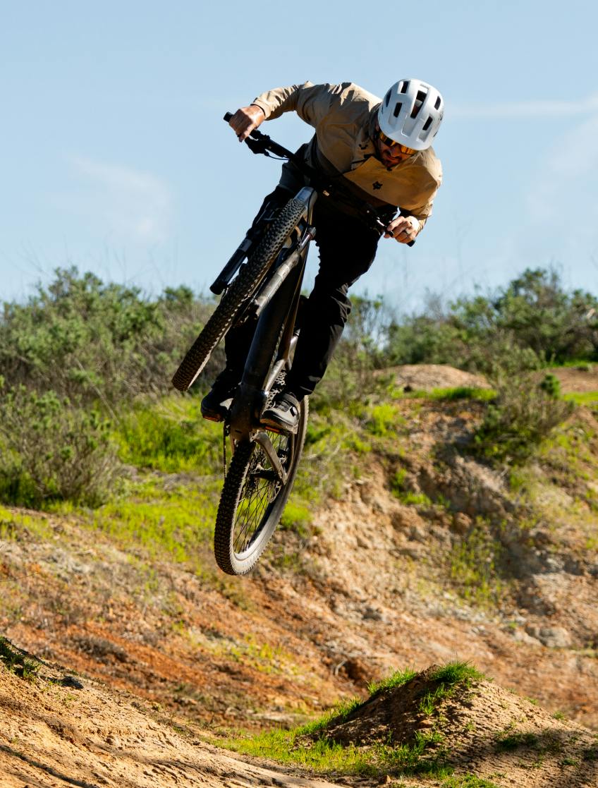 Rider catching air on the Aventon Ramblas ADV electric mountain bike, available at CyclErie in Erie, CO.